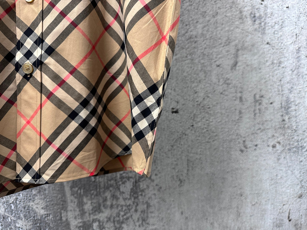 Plaid short-sleeve button-up shirt, side view with sleeve and curved hem