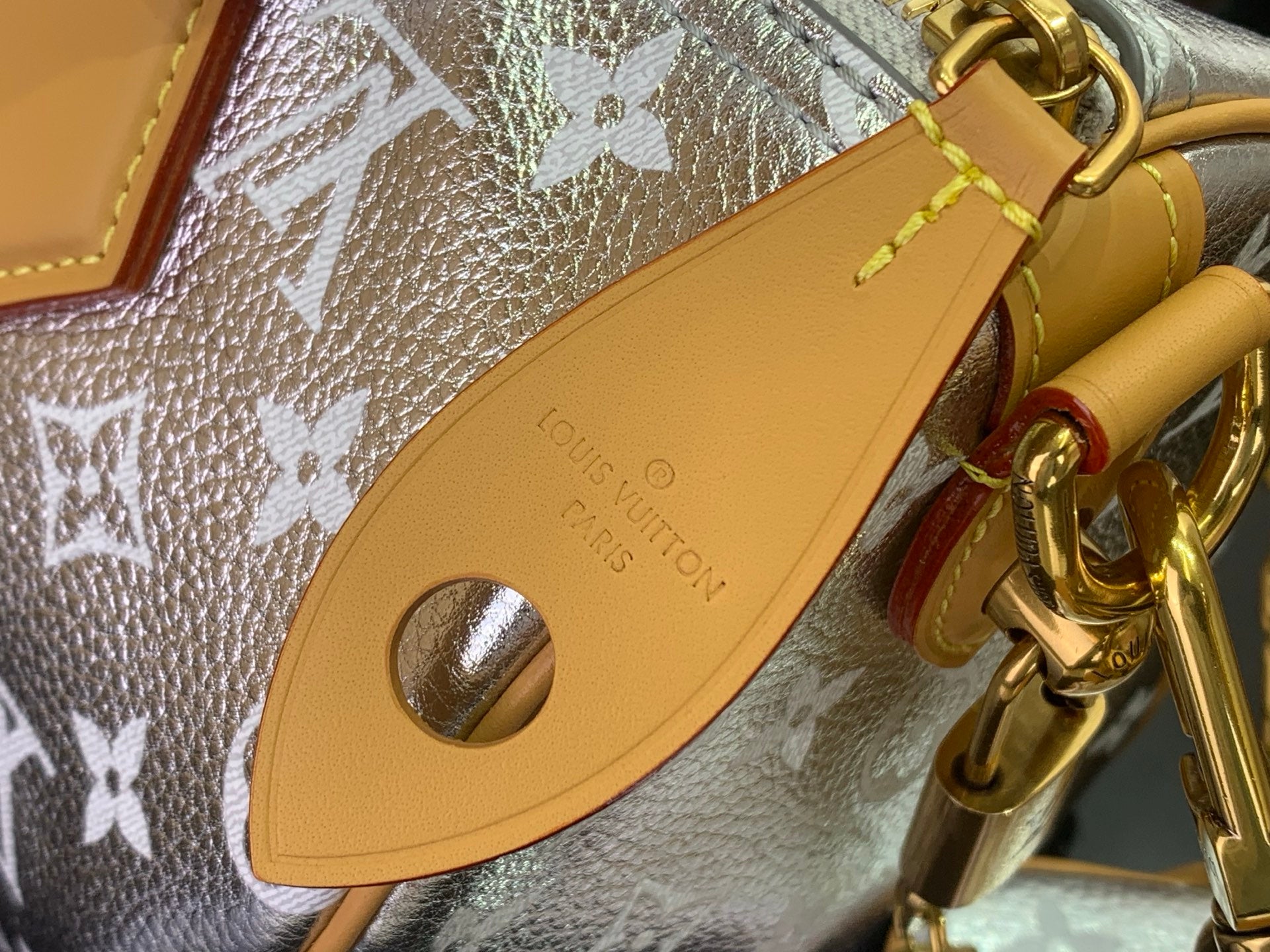 Louis Vuitton strap attachment in tan leather with engraved brand and gold buckle