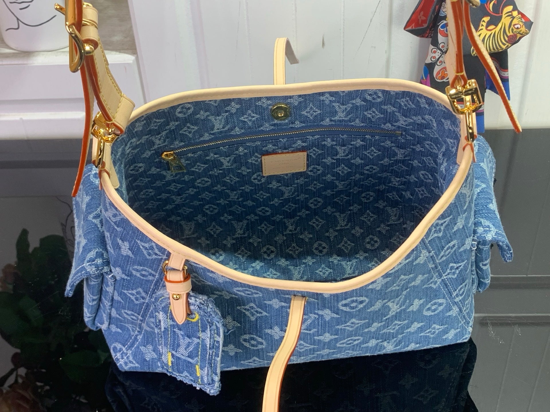 Denim monogram shoulder bag interior with tan piping, zip pull, and gold hardware
