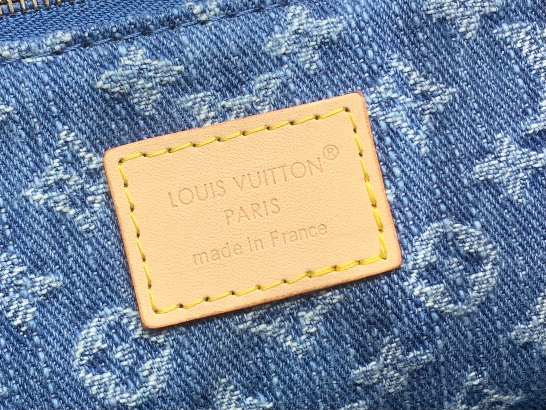Tan leather brand patch with Louis Vuitton PARIS text on denim monogram fabric