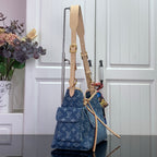 Denim monogram shoulder bag with tan strap, gold clasps, and top handles
