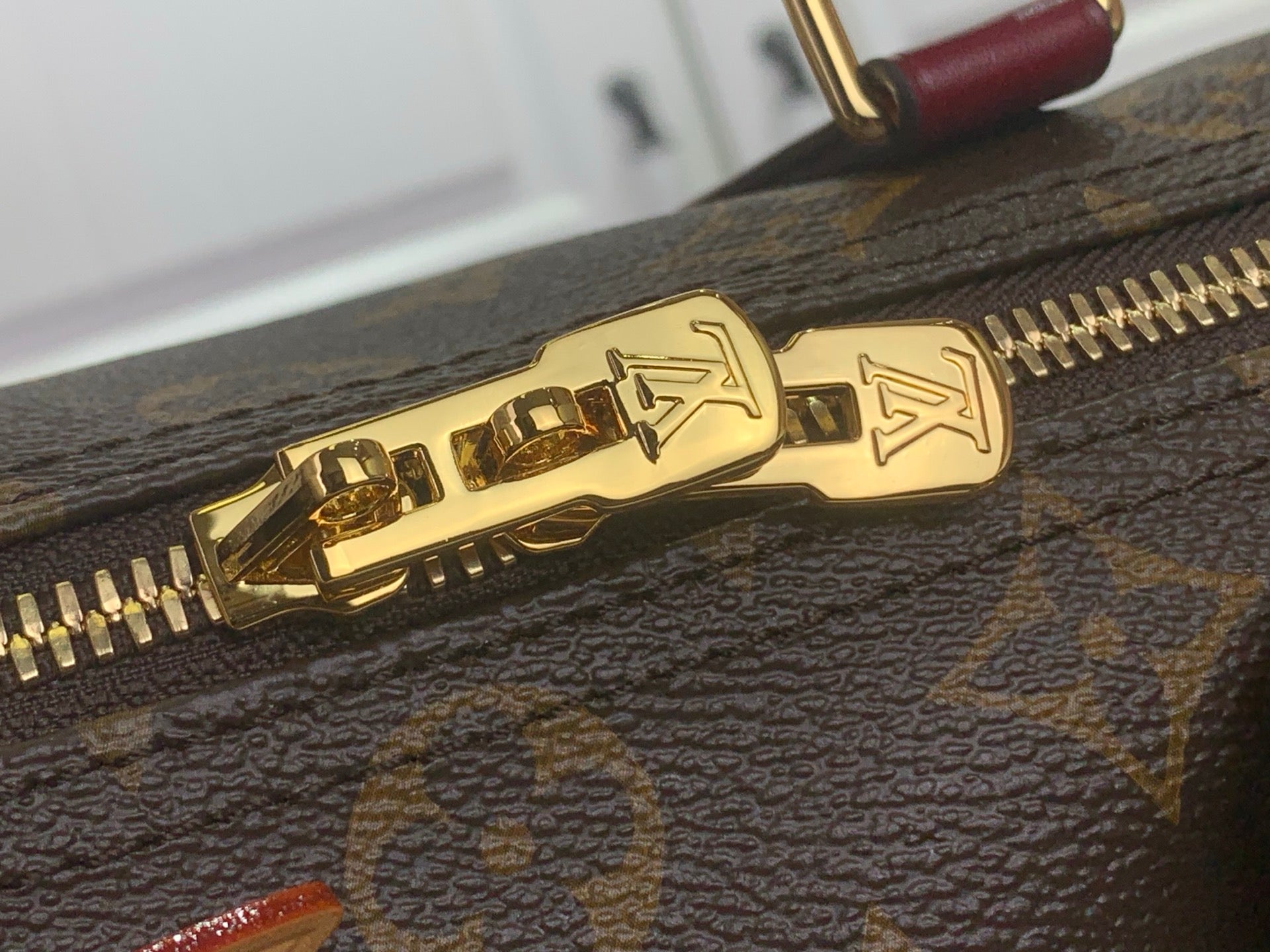 Gold zipper pull and track on monogram bag close-up