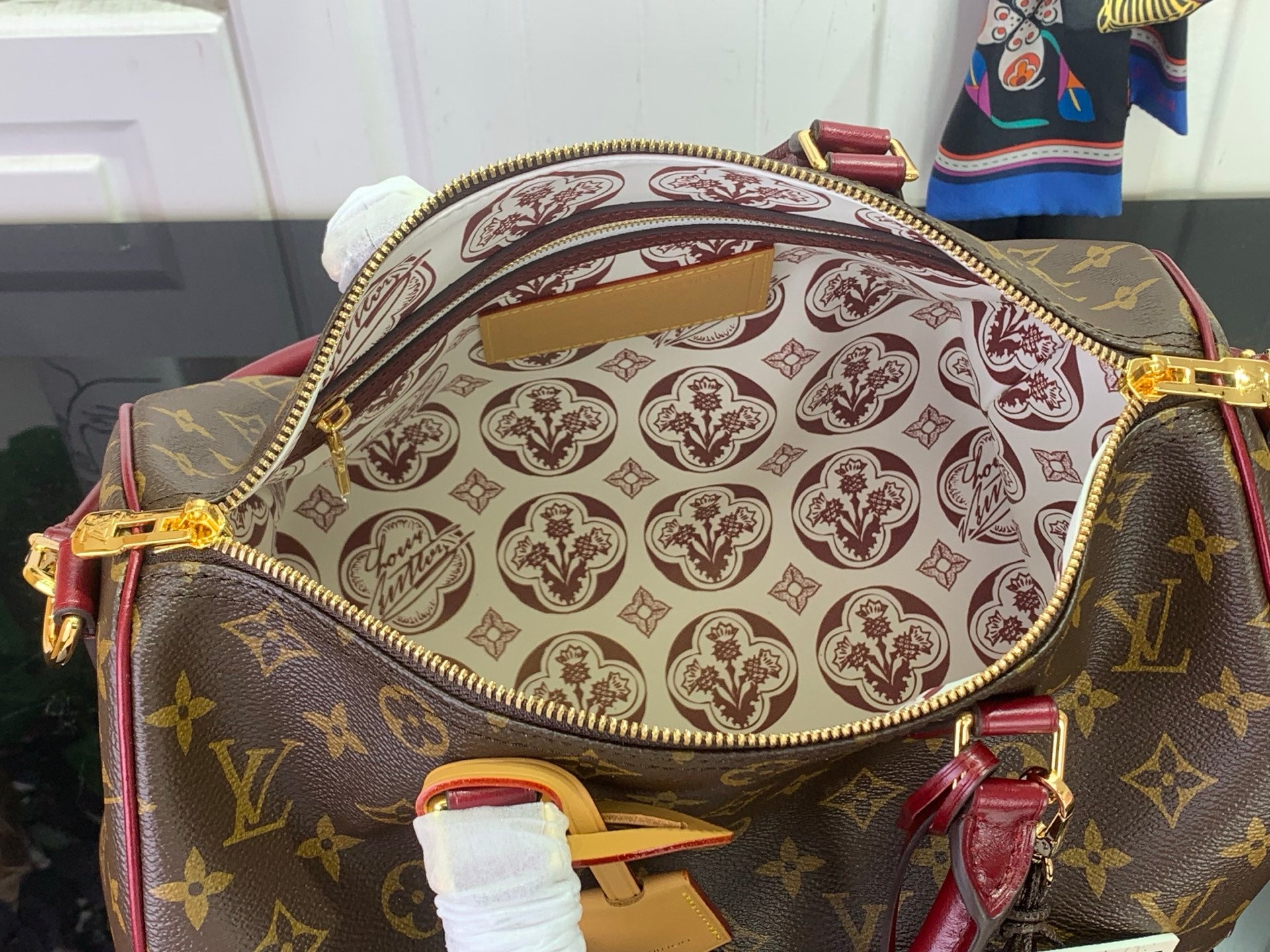Monogram bag interior with patterned lining, zipper edge, and burgundy strap