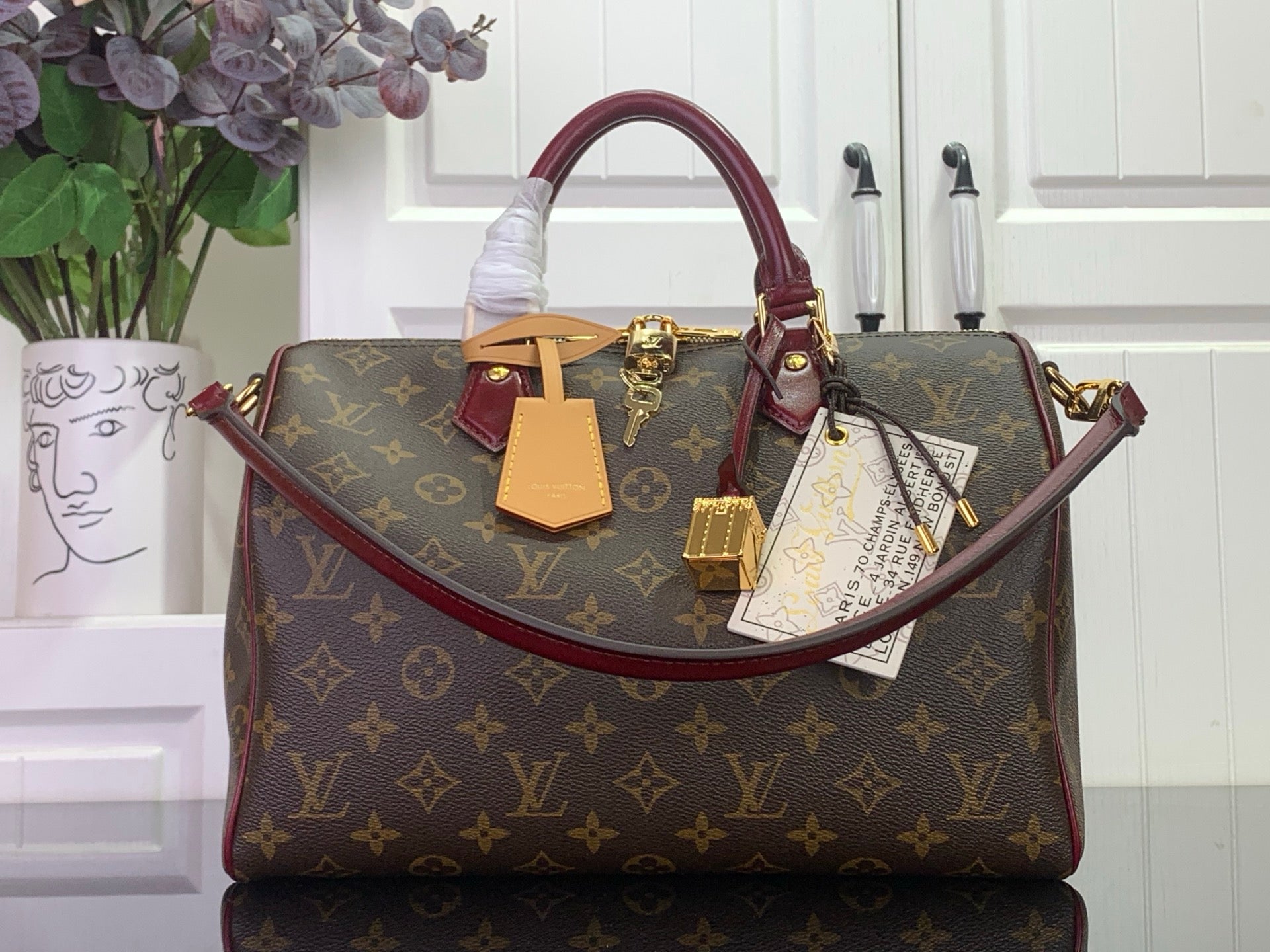 Monogram top-handle bag with burgundy trim and gold hardware