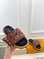 Brown monogram slide sandals in hand with dark navy sole and wide fabric upper