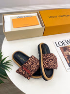 Pair of brown monogram slide sandals with dark navy footbed and wide strap