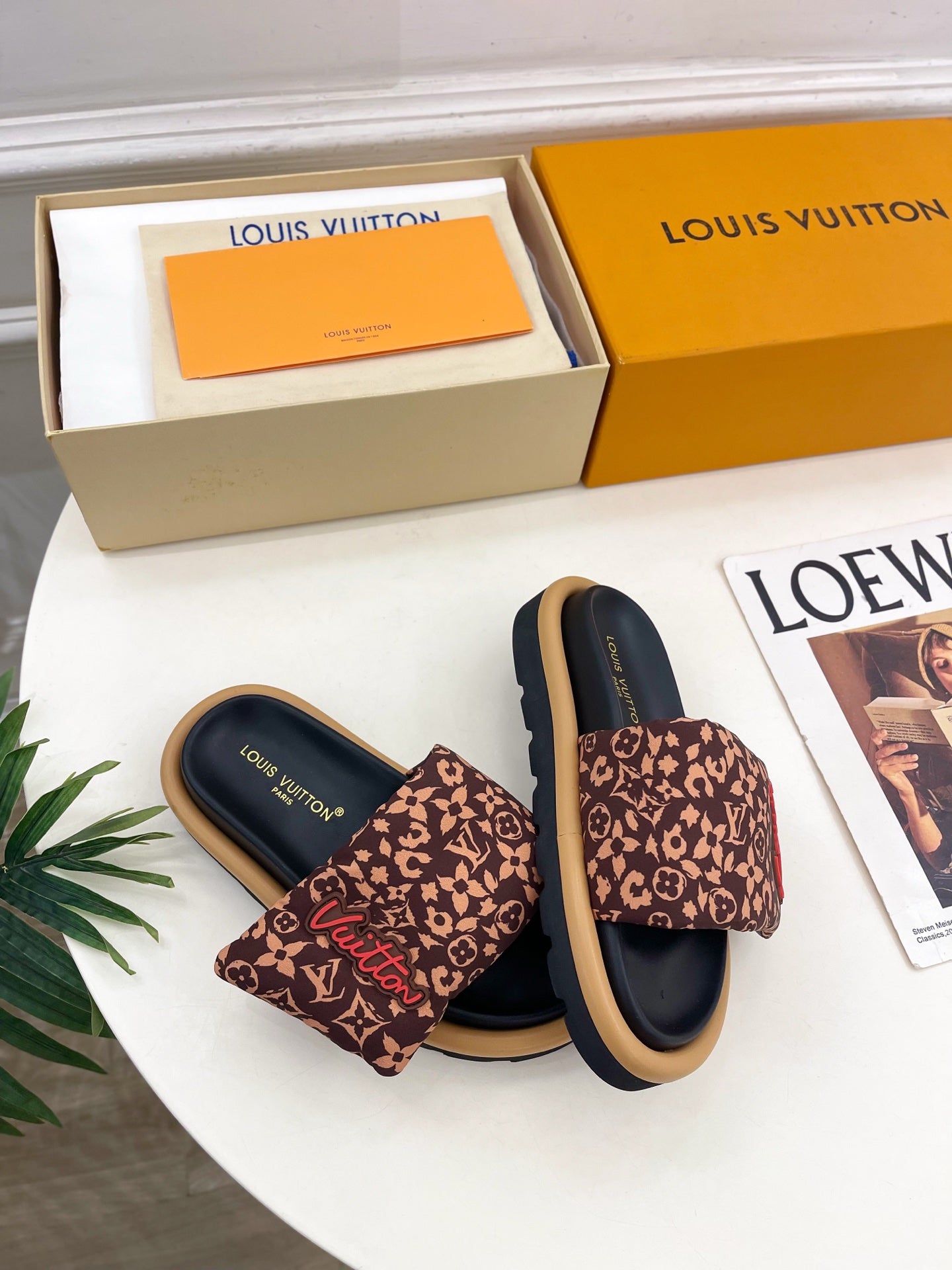 Pair of brown monogram slide sandals with dark navy footbed and wide strap