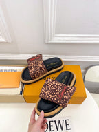 Brown monogram slide sandals shown from side with dark navy sole and footbed