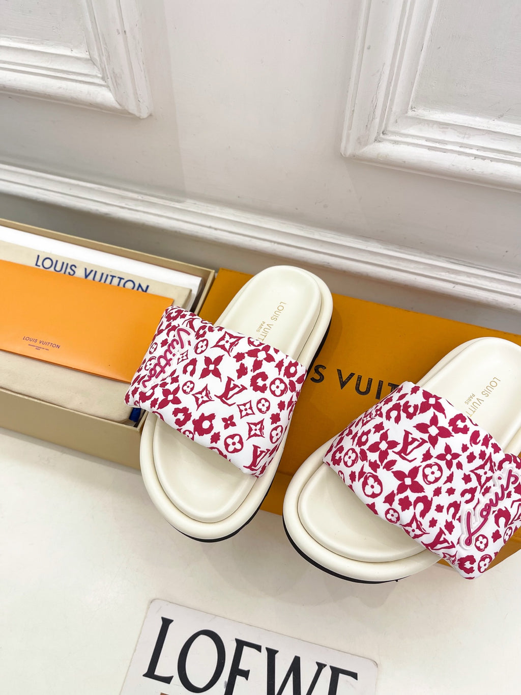 Louis Vuitton slide sandals in white with red patterned straps and black-trimmed soles