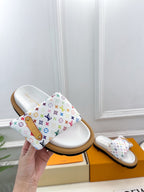 Logo slide sandal held in hand, white footbed with multicolor monogram straps