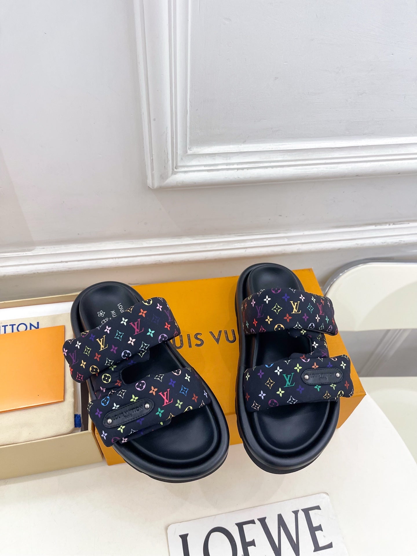 Luxury slide sandals, front view, dark navy upper with multicolor monogram pattern