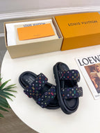 Pair of luxury slide sandals on box; dark navy monogram straps with multicolor print