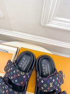Luxury slide sandals, tops visible; dark navy monogram straps with multicolor accents