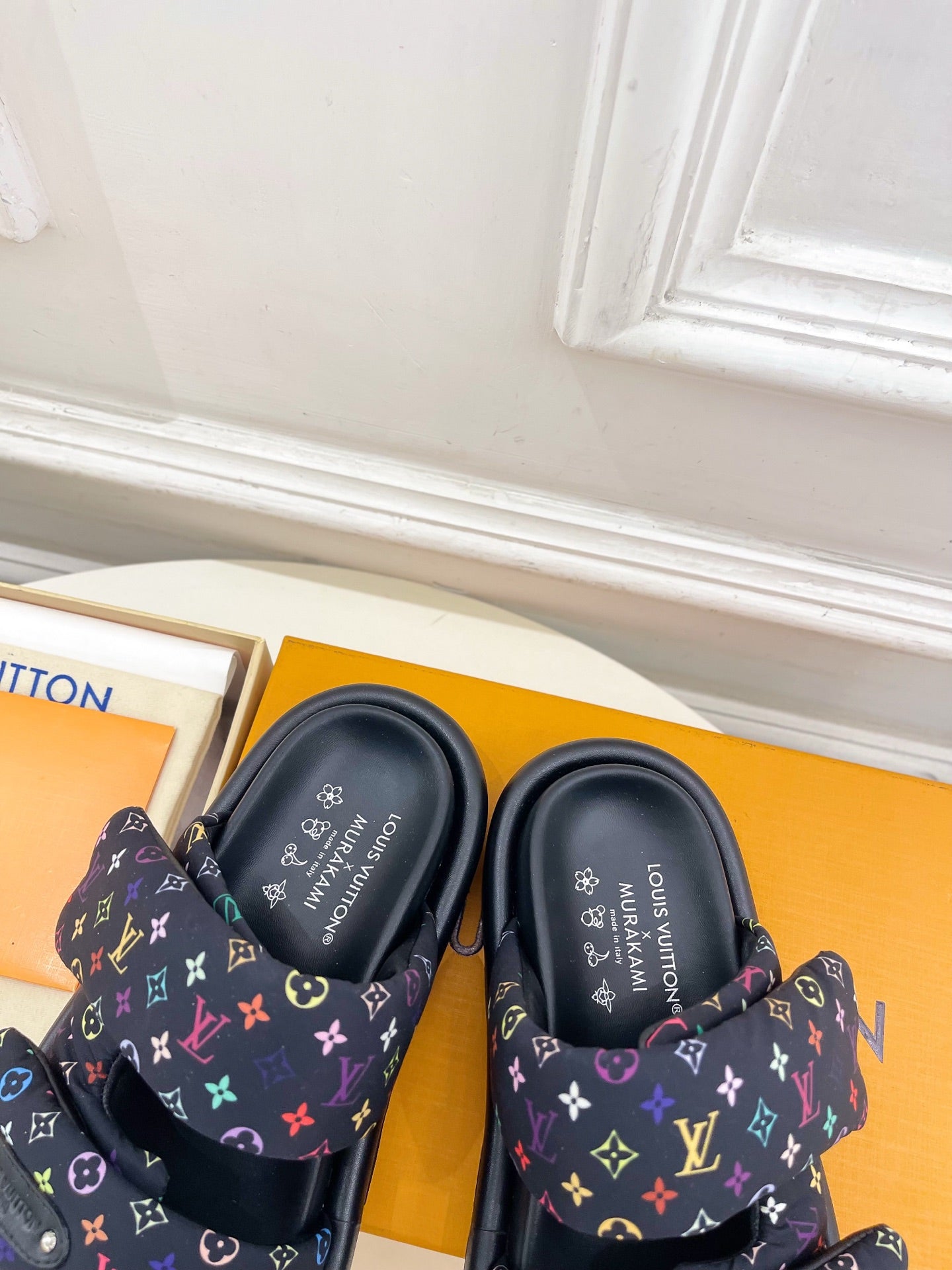 Luxury slide sandals, tops visible; dark navy monogram straps with multicolor accents