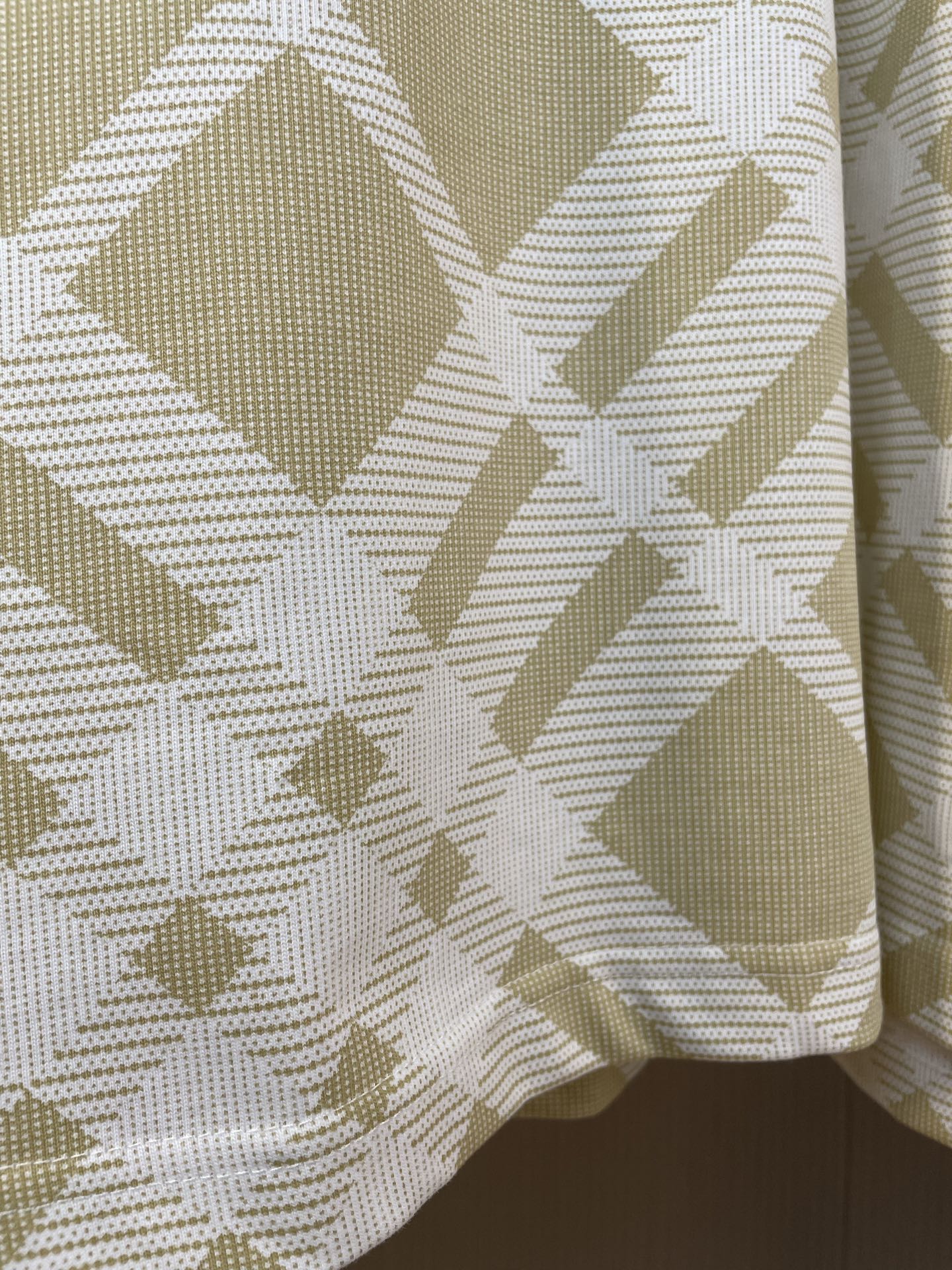 Close-up of yellow-and-white lattice check fabric on a short-sleeve polo