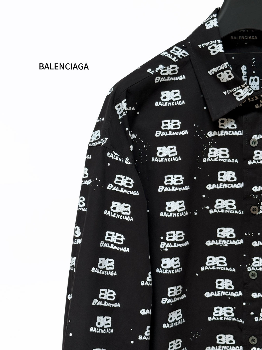 Black long-sleeve shirt close-up of spread collar with Balenciaga logo pattern.