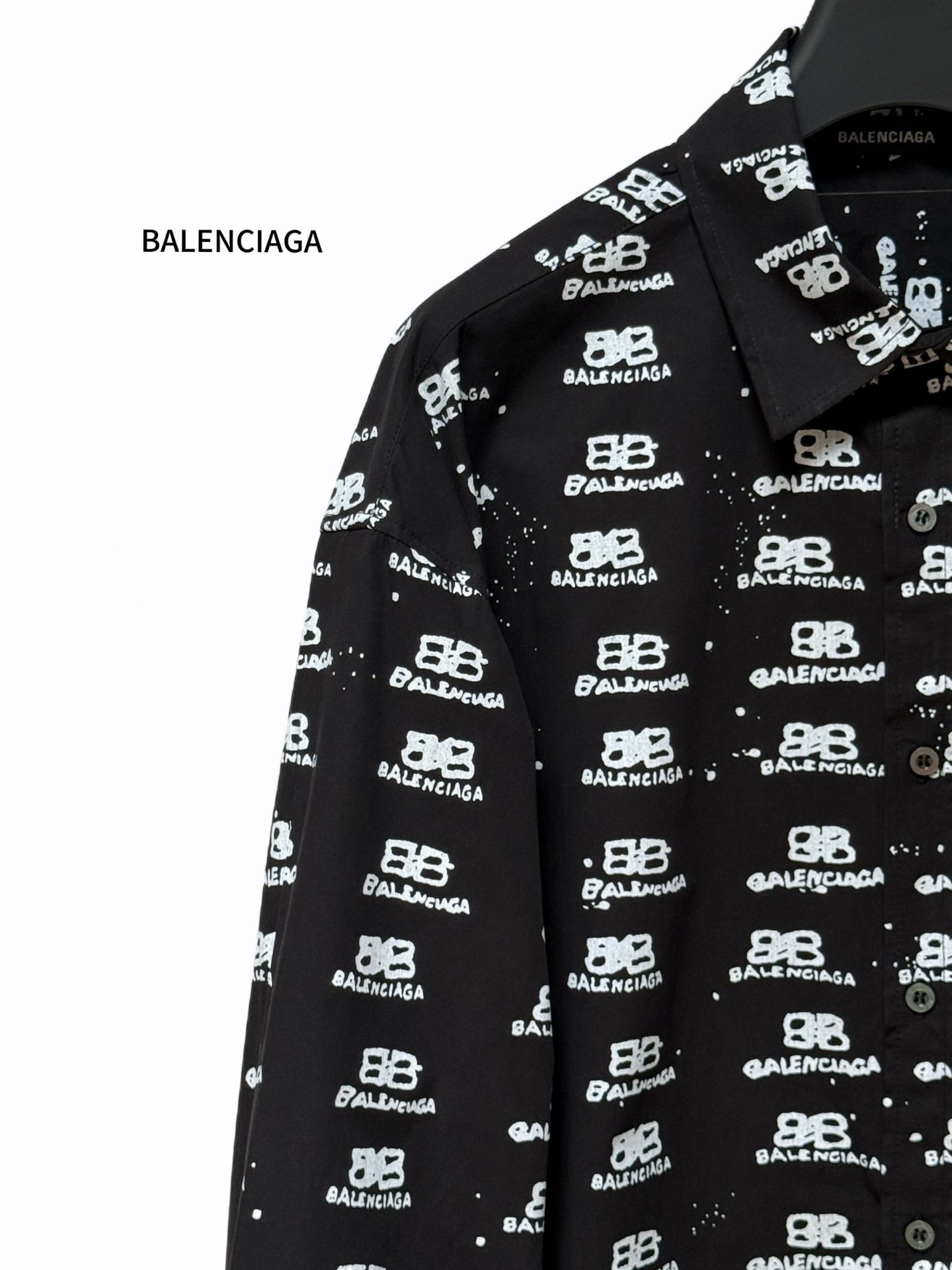 Black long-sleeve shirt close-up of spread collar with Balenciaga logo pattern.