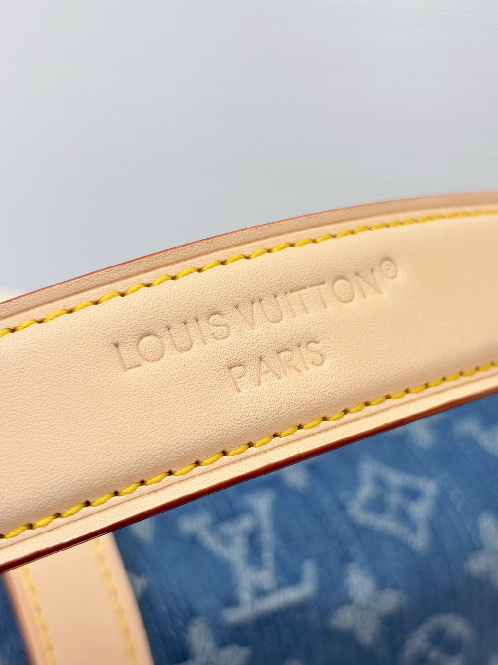 Louis Vuitton bag close-up of Louis Vuitton Paris stamp on white leather strap edge