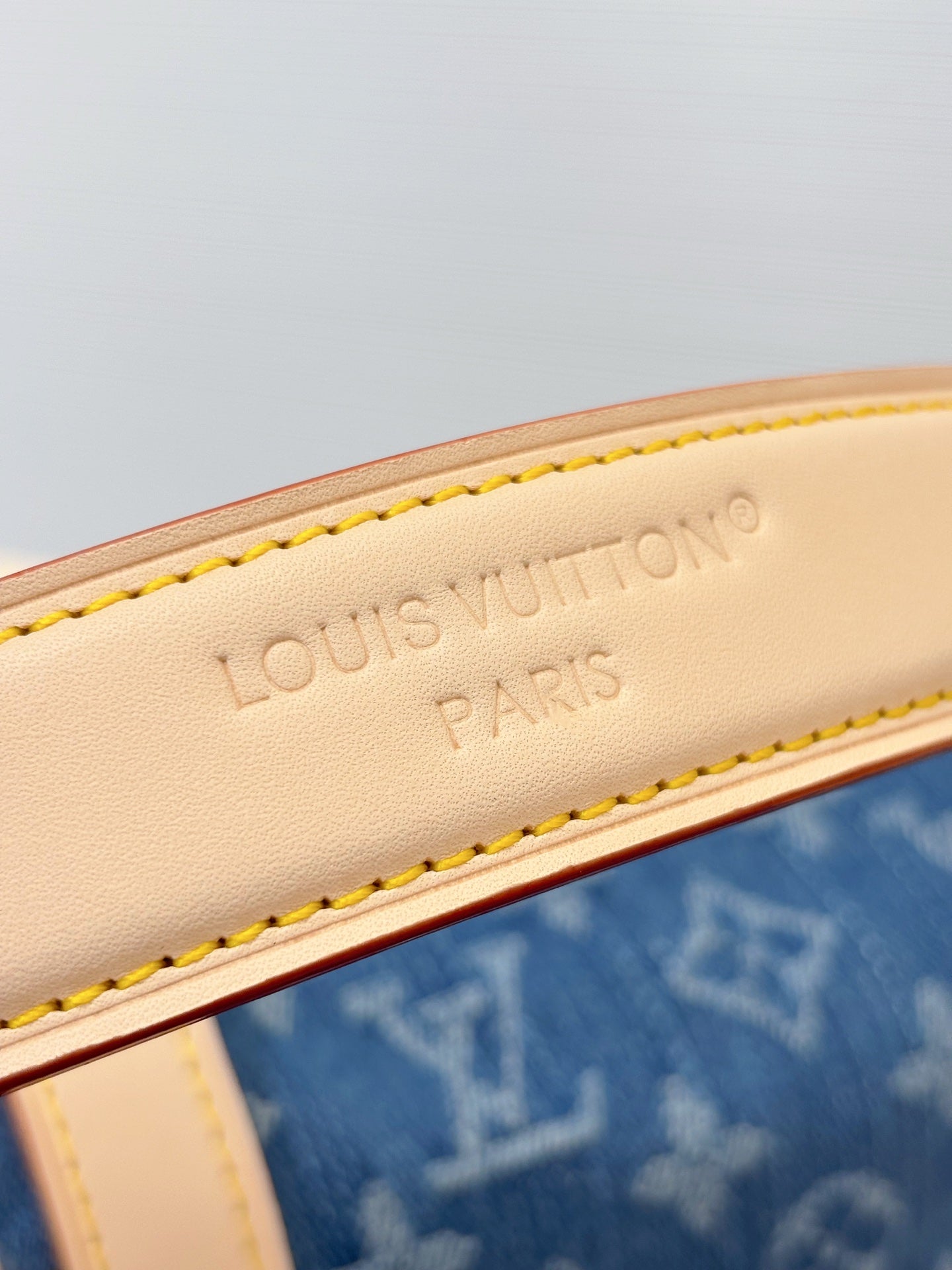 Louis Vuitton bag close-up of Louis Vuitton Paris stamp on white leather strap edge