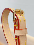 Louis Vuitton bag close-up of red strap detail with white leather and gold buckle