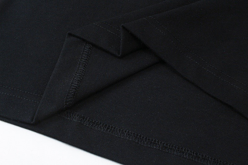 Black T-shirt hem with side seam and stitched detail close-up