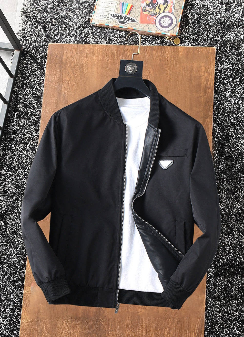 Black zip-up jacket with stand collar, front zipper, and logo chest patch