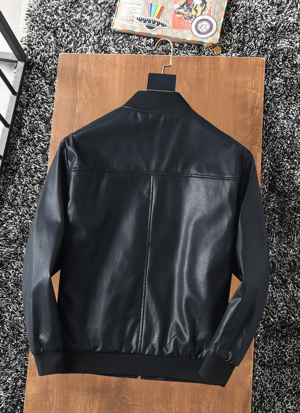 Black zip-up jacket back view with stand collar and ribbed hem