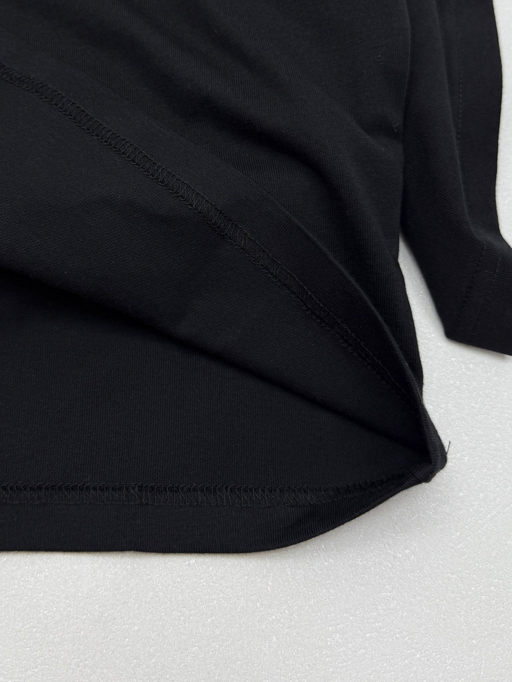Black short-sleeve T-shirt fabric with visible side stitching at hem