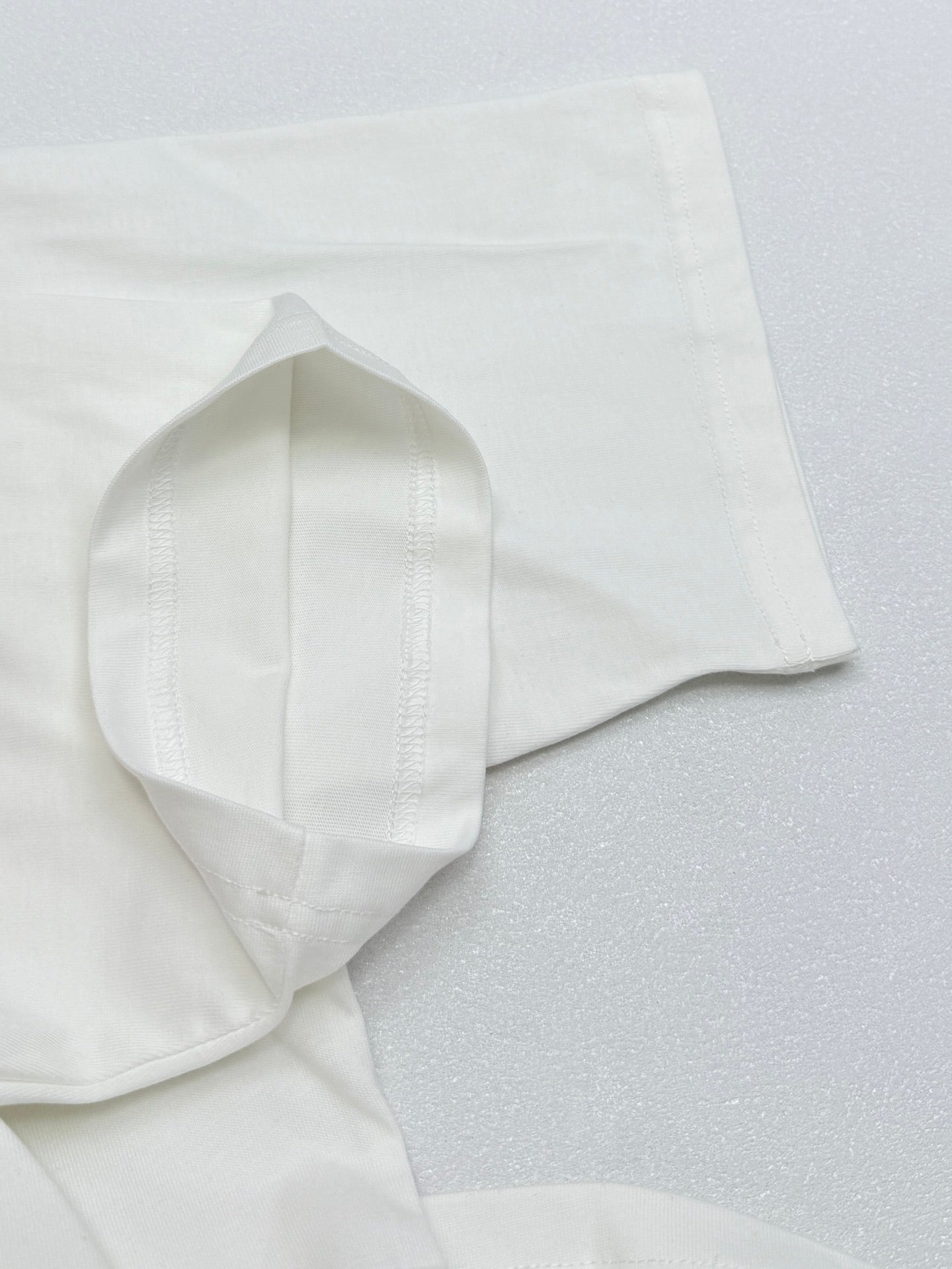 White T-shirt sleeve and hem seam detail on folded fabric.