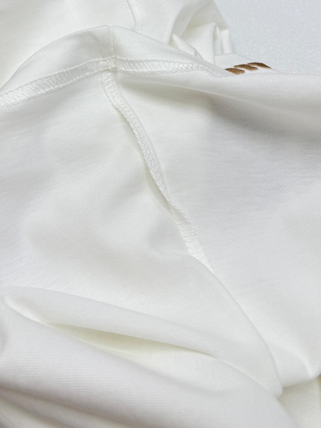 White T-shirt fabric close-up with stitched side seam.