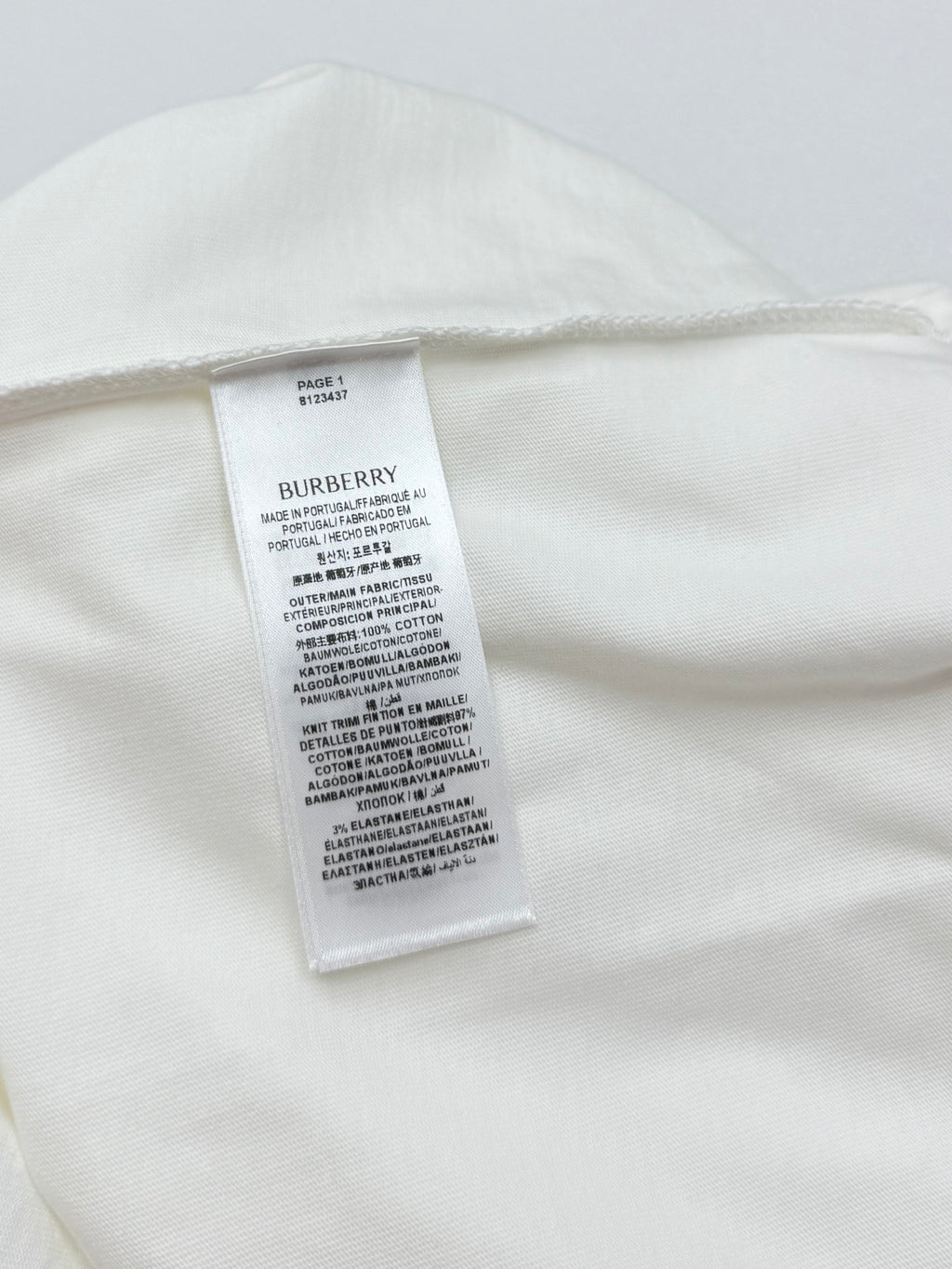 White T-shirt with internal care label stitched near the back neck.
