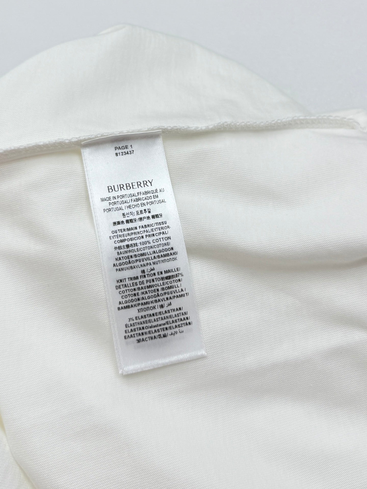 White T-shirt with internal care label stitched near the back neck.