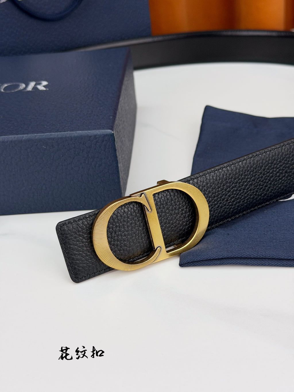 Dior belt close-up with gold CD buckle on textured dark leather strap.