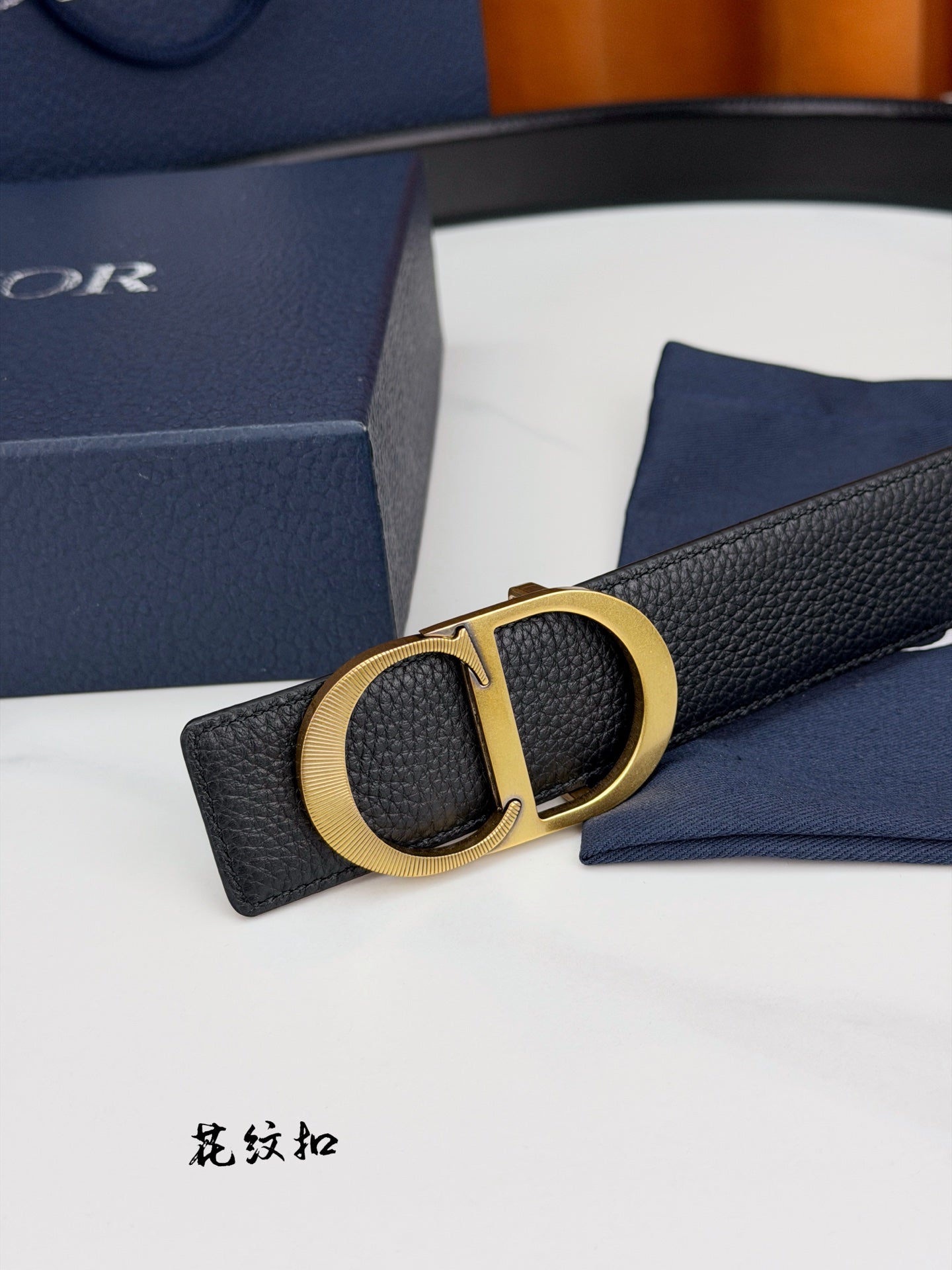 Dior belt close-up with gold CD buckle on textured dark leather strap.
