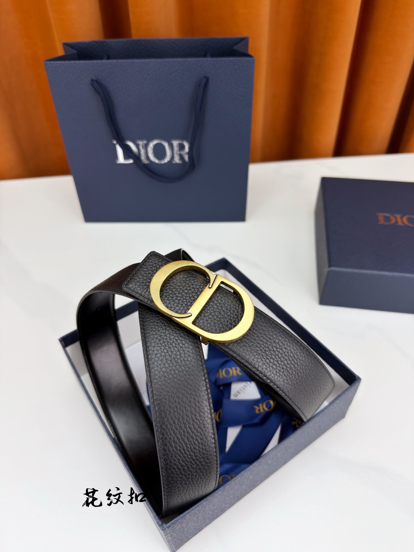 Dior belt with dark leather strap and gold CD buckle on display.