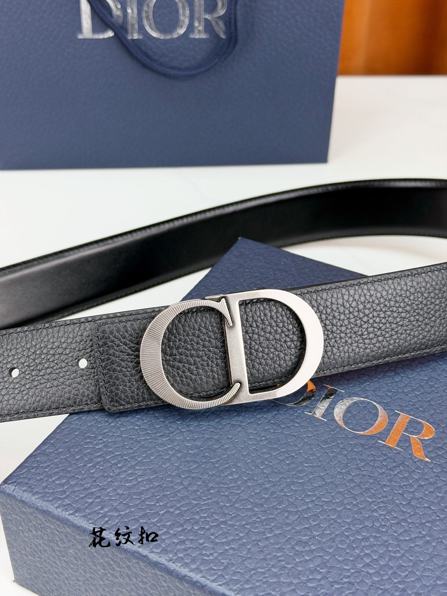 Dior belt close-up with silver CD buckle on dark leather strap.
