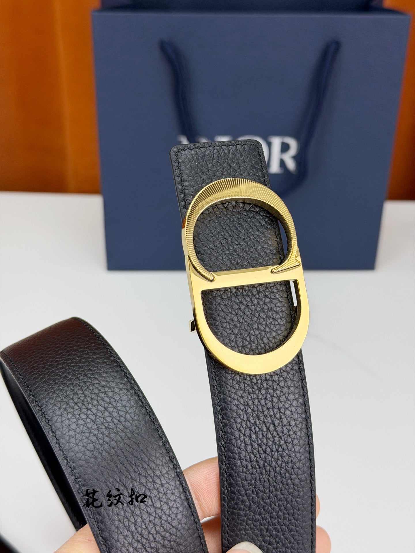 Dior belt close-up with dark textured leather strap and gold-tone buckle ring