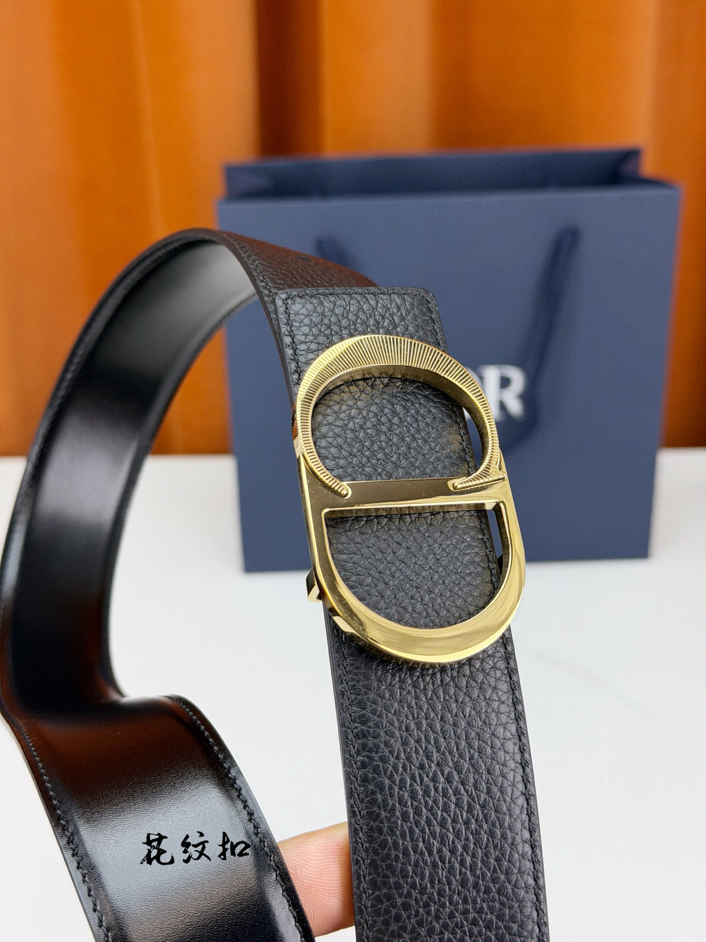 Dior belt close-up: dark textured leather with gold-tone D buckle