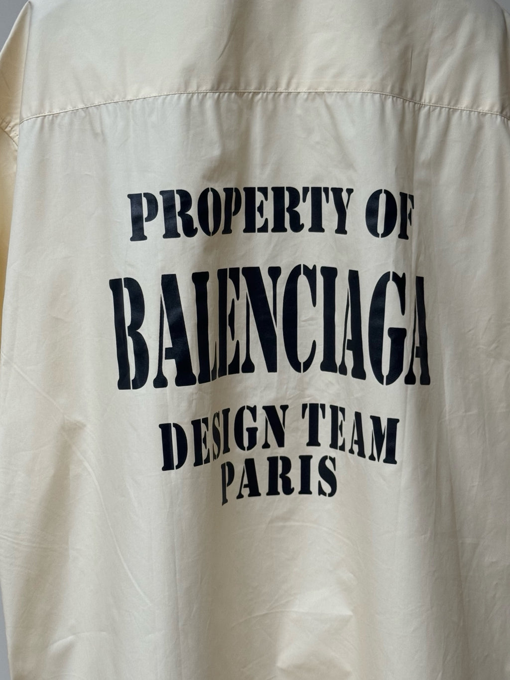 Cream short-sleeve button-up shirt back graphic: PROPERTY OF BALENCIAGA DESIGN TEAM PARIS