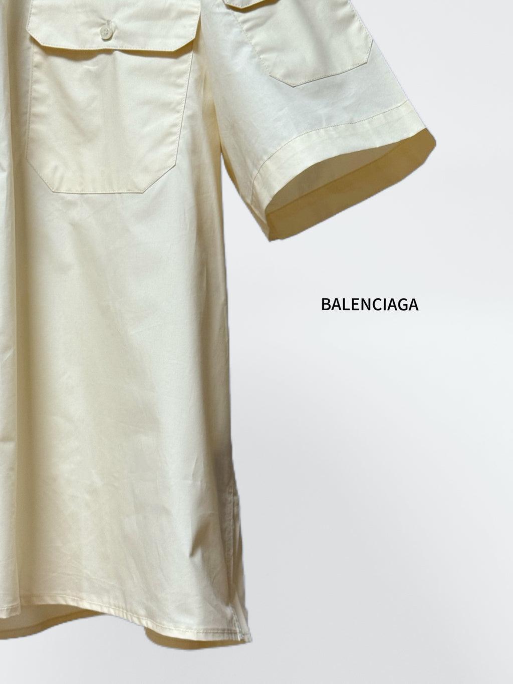 Cream short-sleeve button-up shirt with chest pockets and curved sleeve cuff