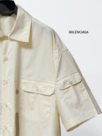 Balenciaga cream short-sleeve button shirt with flap pockets and stitched seam detailing.