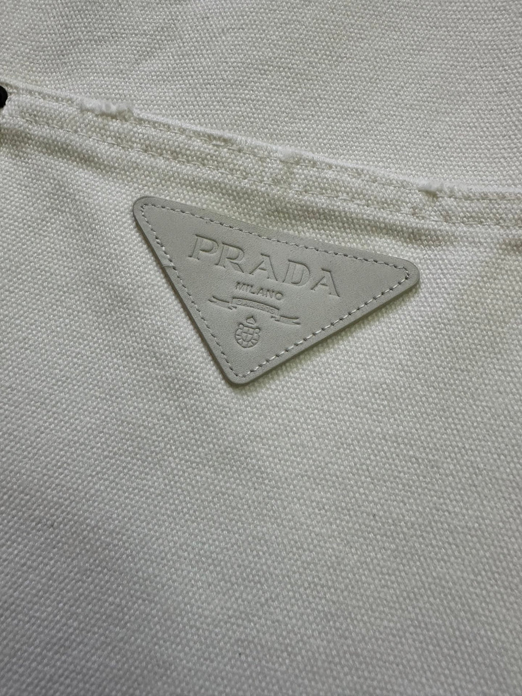 Prada triangular logo patch on white fabric