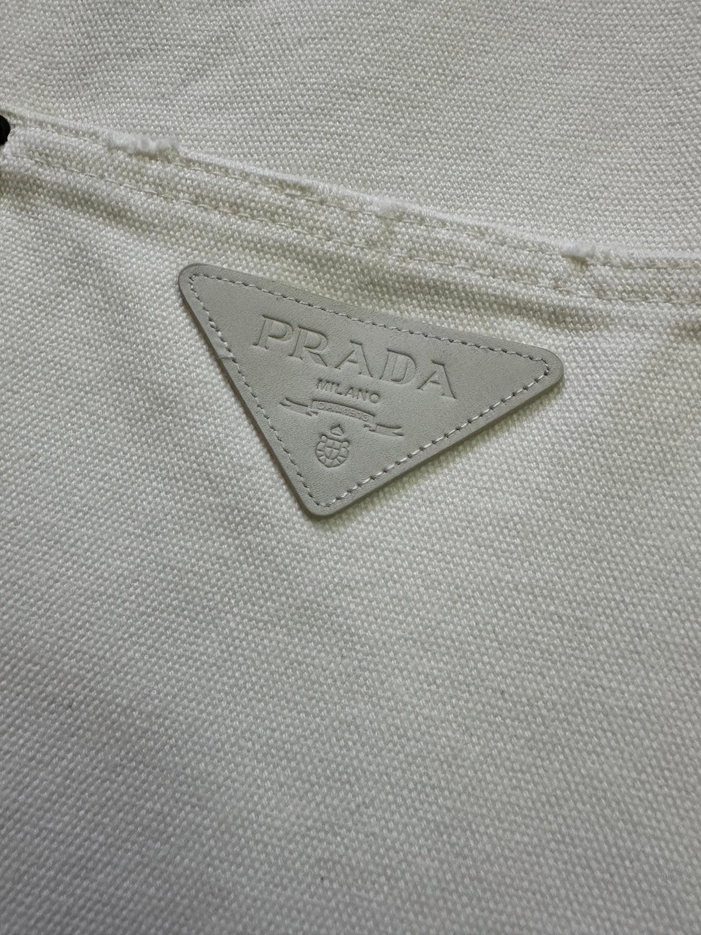 Prada triangular logo patch on white fabric