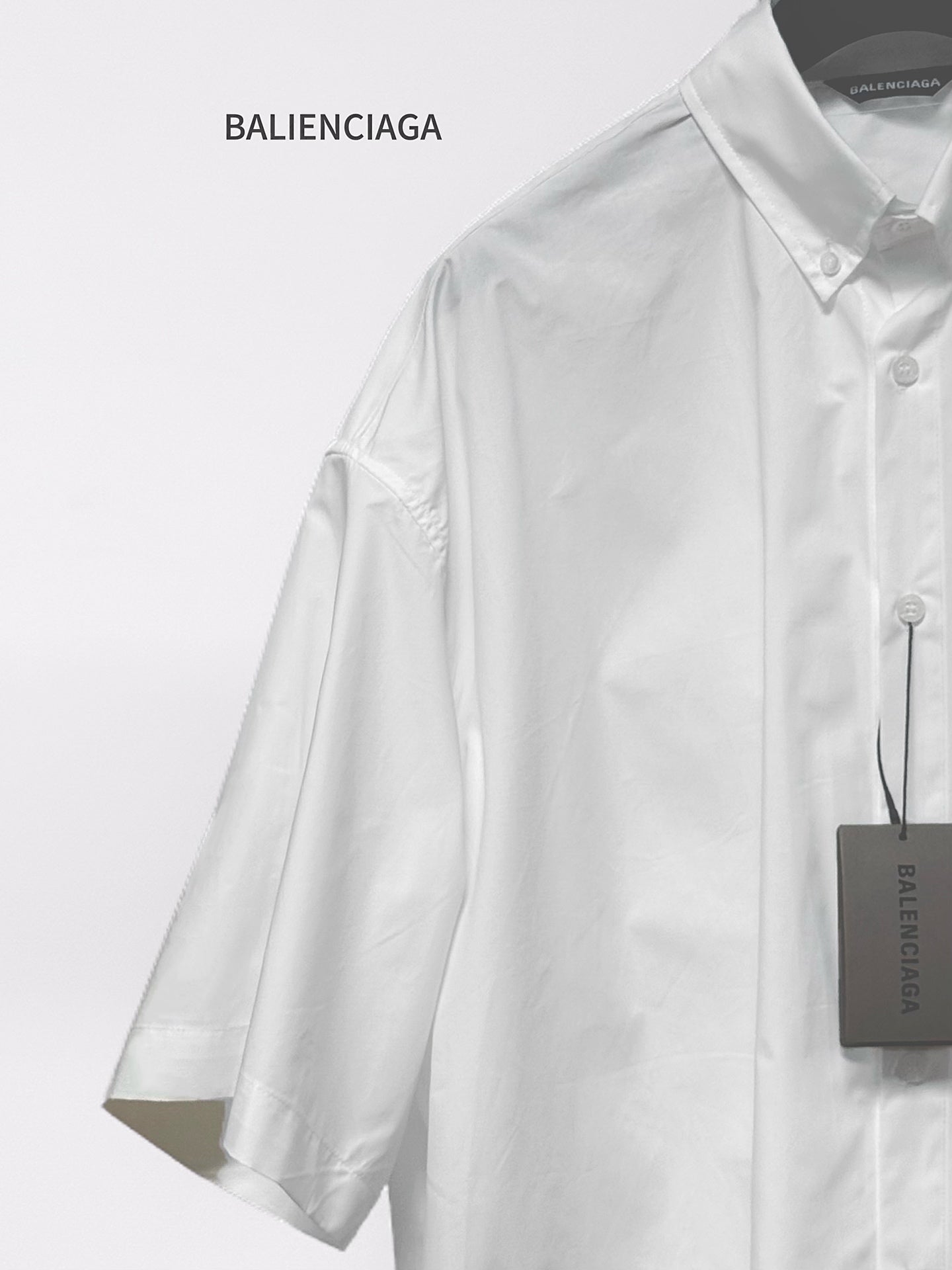 Balenciaga white long-sleeve button-up shirt with visible buttons and hanging tag