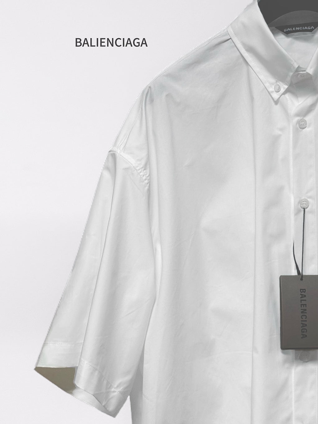 Balenciaga white short-sleeve button-up shirt close-up of shoulder, sleeve, and tag
