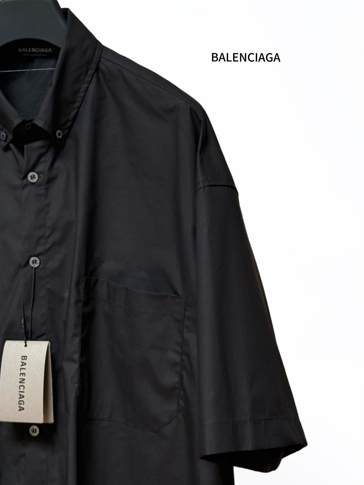 Men's short-sleeve button-up shirt, black, angled view with chest pocket detail