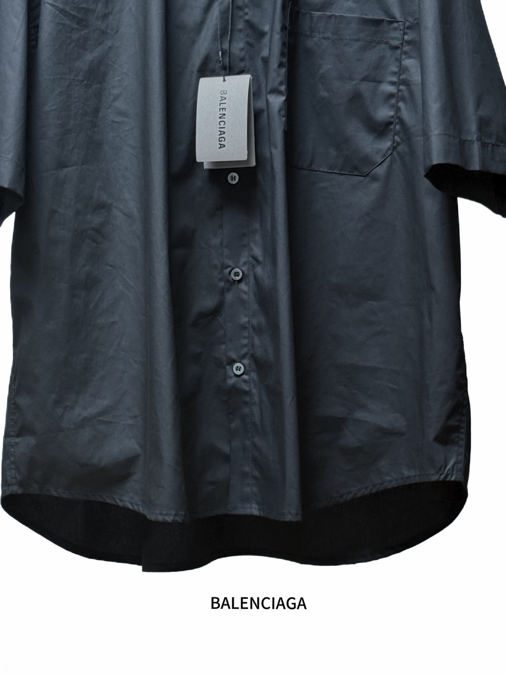 Black short-sleeve shirt with button-front and chest pocket, lower hem view