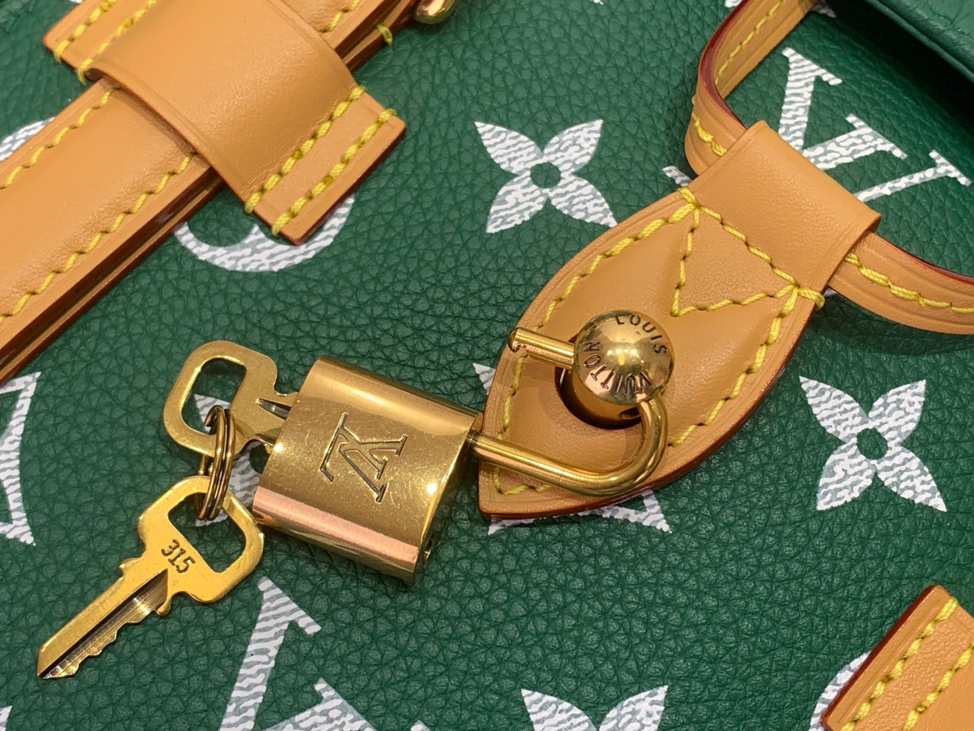 Louis Vuitton green monogram handbag with tan leather hardware and gold clasp close-up