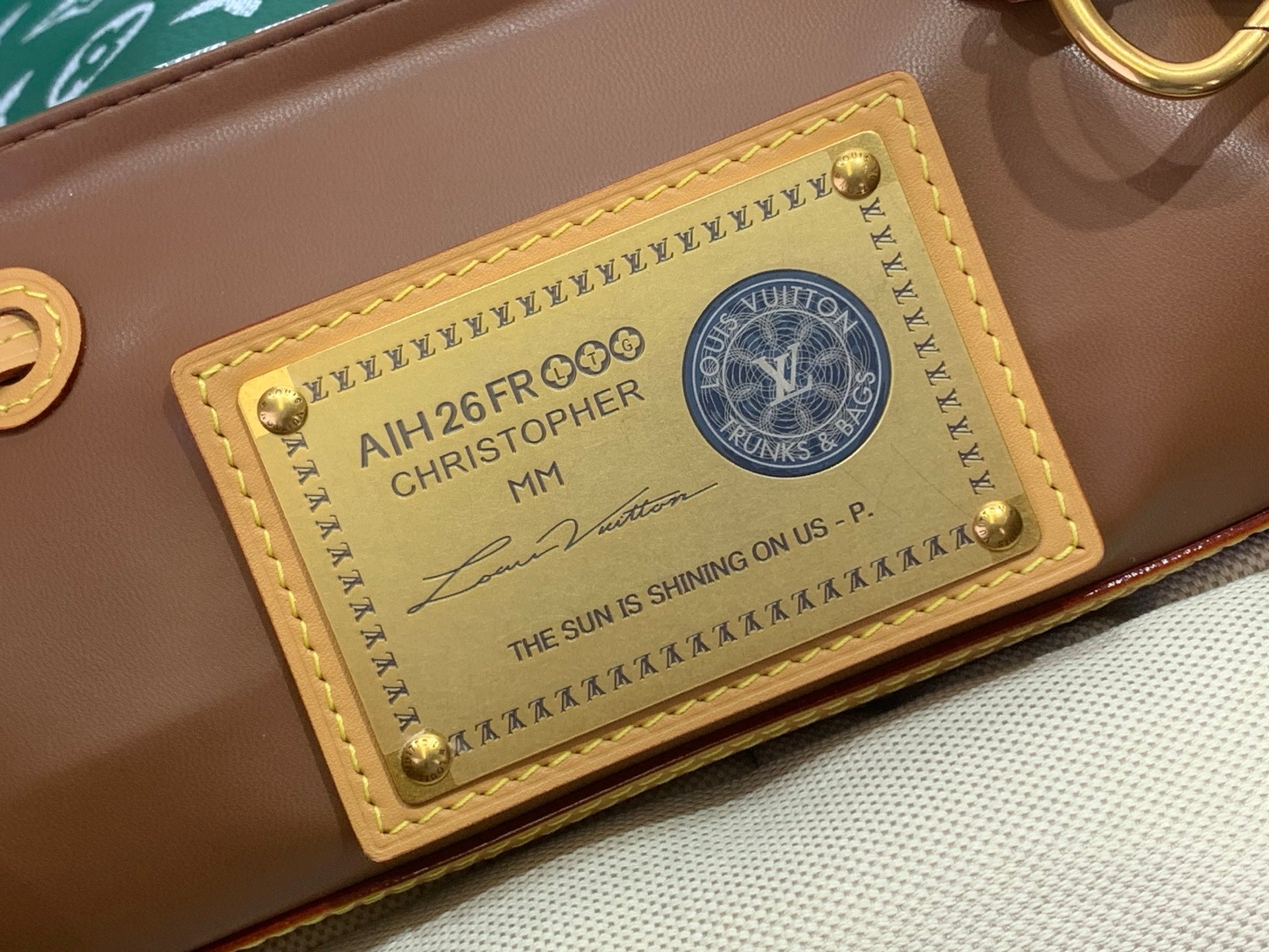 Louis Vuitton luggage tag on brown leather base with printed text and round seal