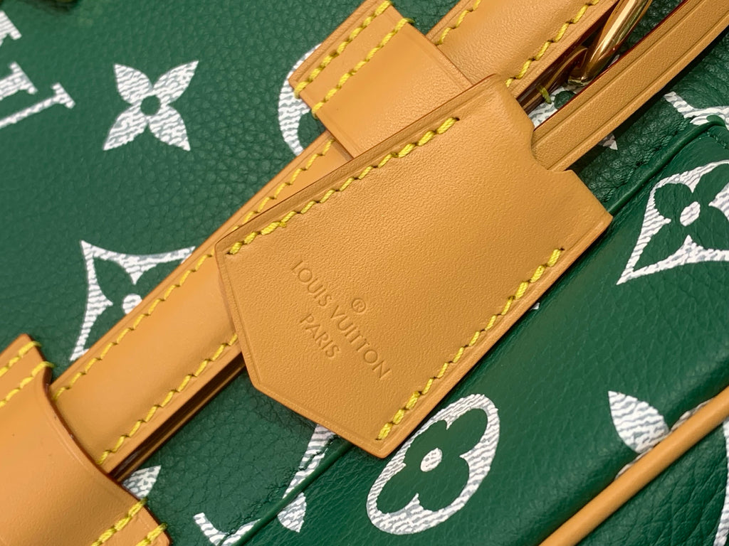 Louis Vuitton tan leather strap tab with engraved brand and gold rivets on green monogram
